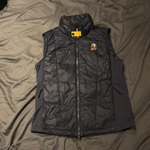 Mörkblå dunväst från Parajumpers - Säljer en snygg mörkblå dunväst från Parajumpers med dragkedja som knappt är använd. Västen är i tunnt material då den är perfekt o ha på soliga varma dagar.