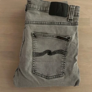 Nudie jeans - Snygga grå jeans från Nudie Jeans med en klassisk femficksdesign. De har en normal passform och är tillverkade i slitstarkt denim. Perfekta för en avslappnad stil. Inga deffekter bara höra av sig vid eventuella funderingar!