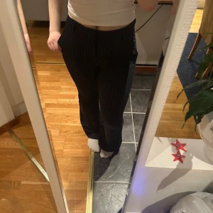 Mörkblå randiga kostymbyxor - Mörkblå, nästan svarta kostymbyxor med tunna vita ränder. Byxorna har en hög midja och en utsvänga ben. Bra kvalitet, knappt använda, buda gärna 🥰Står ingen storlek men jag tycker de är som 38/40