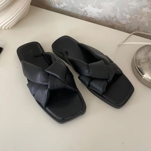 Svarta sandaler från H&M - Snygga svarta sandaler från H&M med en unik flätad design. De har en fyrkantig tå och är perfekta för en stilren look.