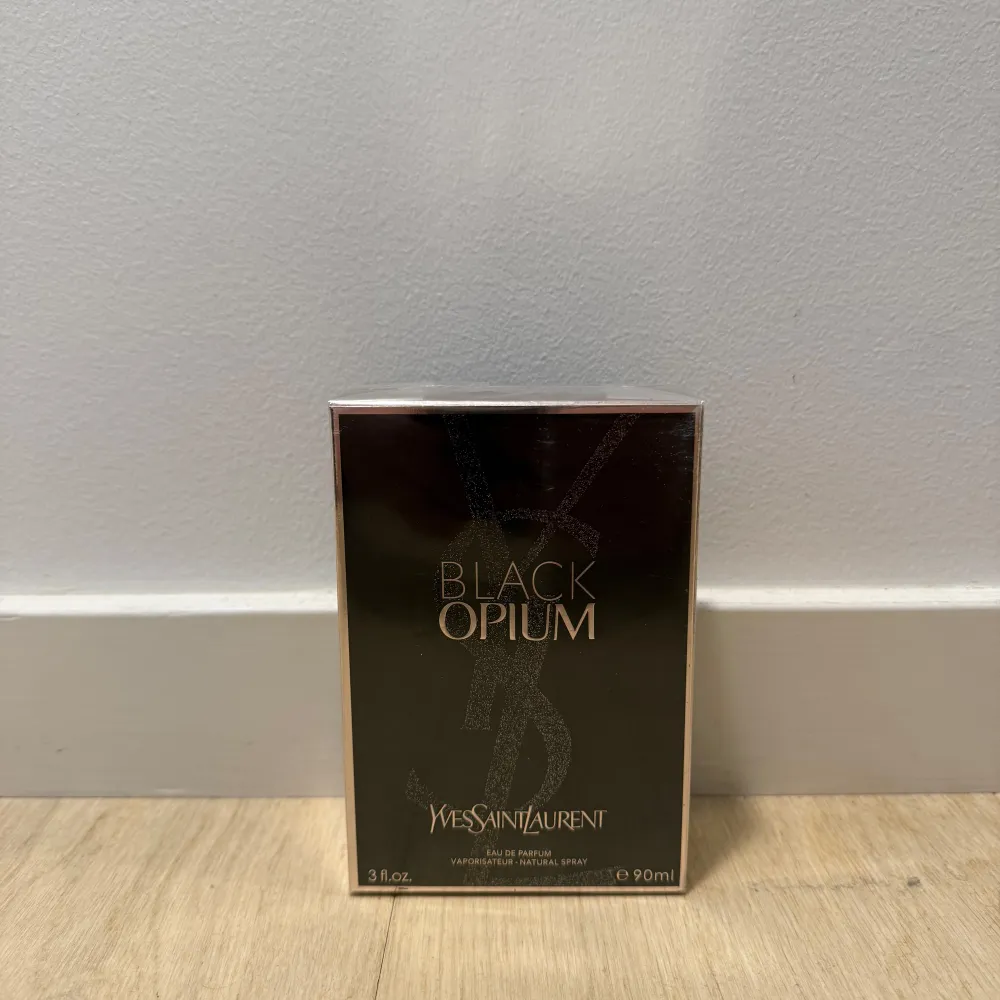 Säljer en elegant Black Opium parfym från Yves Saint Laurent. Flaskan rymmer 90 ml och kommer i en stilren svart förpackning med guldtext. Flaskan i sig passar bra på hyllan för en extra inredningsdetalj. Perfekt för tjejen som älskar en sensuell doft. En lyxig doftupplevelse för speciella tillfällen. Den är aldrig använd och plasten sitter kvar på lådan.. Perfume.