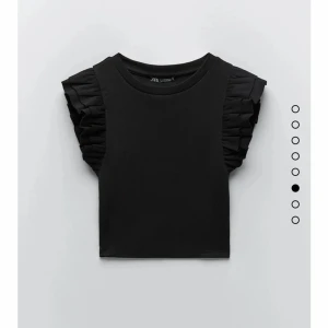 Svart topp med volangärmar från Zara - Snygg svart topp från Zara med volangdetaljer på ärmarna. Perfekt för att ge en stilren look med en twist. Toppen har en rund halsringning och är tillverkad i ett mjukt material.