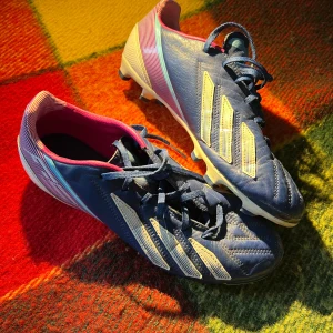 Blå fotbollsskor från Adidas - Blå fotbollsskor från Adidas med vita och rosa detaljer. 