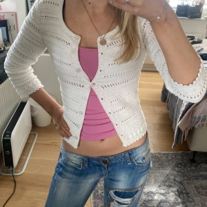 Vit stickad kofta - Säljer en söt vit stickad kofta med ett hålmönster. Koftan har långa ärmar och en rund halsringning. Perfekt för lager-på-lager-stil och passar till många olika outfits.