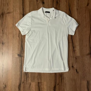 Vit kortärmad pikétröja - Säljer en klassisk vit kortärmad pikétröja från Berkeley. Perfekt för en stilren och avslappnad look. Tröjan har en krage och knappar framtill.