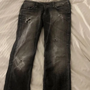 Gråsvarta lågmidjade bootcut jeans  - Säljer dessa supersnygga lågmidjade jeans som är utsydda till bootcut. De är svarta med en grå tvätt och sjukt snygga hål som syns tydligare på sista bilden💗 från tommy hilfiger i storlek 29/32