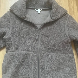 teddyjacka från hm  - Mysig grå teddyjacka med dragkedja framtill. Jackan har långa ärmar och två fickor framtill. Från hm storlek xs