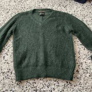 Grön stickad tröja från Scotch & Soda - Snygg grön stickad tröja från Scotch & Soda med v-ringning. Jätte fin går att användas av båda könen. Säljer då jag inte får någon användning av den. Original pris:2000kr, ny skick.