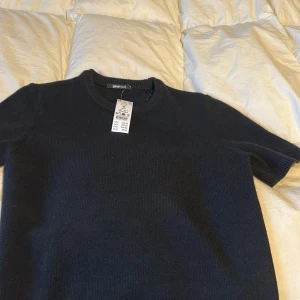 Svart stickad topp från Gina Tricot - Säljer en stilren svart stickad topp från Gina Tricot. Den har korta ärmar och en rund halsringning, perfekt för en minimalistisk look. Passar bra till både jeans och kjol. 🖤 Säljer den då jag råkat beställa hem fel storlek!!