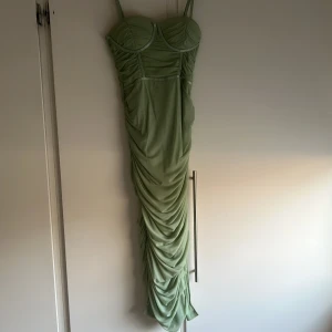 Grön axelbandslös långklänning - Elegant mint grön festklänning med smala axelband och rynkade detaljer. Klänningen har en figurnära passform. Endast använt 1 gång. Kontakta för fler bilder. Storlek Xs