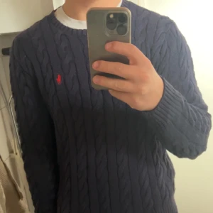 Marinblå stickad tröja från Ralph Lauren S/M - Säljer en snygg marinblå stickad tröja från Ralph Lauren med kabelstickat mönster. Tröjan har en liten röd logga på bröstet och rund halsringning. Perfekt för kyliga dagar! Skick 10/10, knappt använd. Nypris 2200kr. Säljs då den sitter lite för tight på mig som ni kan se på bilderna. Storlek är S men sitter mer som M. Hör av dig vid eventuella frågor och priset är diskuterbart.😊⭐️