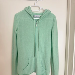Mintgrön kashmir hoodie från KAS&KAAN - Säljer en supermjuk mintgrön hoodie i 100% kashmir från KAS&KAAN. Den har dragkedja framtill och praktiska fickor. Perfekt för kyliga dagar när du vill vara både bekväm och stilren. 💚