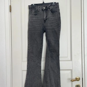 Grå bootcut jeans - Säljer ett par gråa bootcut jeans med låg midja. Jeansen har klassiska fem fickor, dragkedja och knapp framtill. Perfekta för dig som gillar en retroinspirerad look med utsvängda ben.
