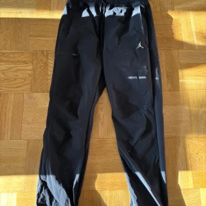 Svarta Jordan byxor med snörning - Säljer ett par svarta byxor från Jordan med elastisk midja och snörning. Byxorna har raka ben, en ficka på sidan och den klassiska Jumpman-loggan broderad framtill. Perfekt för träning eller liknande.
