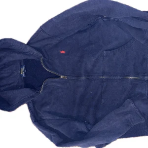 Marinblå zipup tröja från Ralph Lauren - Säljer en väldigt snygg Polo Ralph Lauren Zip Up med inga fläckar, inga skador. Den passar slim fit och är mer S/M. Perfekt för en stilren utseende och är av väldigt hög kvalité. (Tvättlappen har blivit klippt)