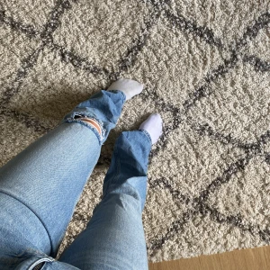 Ljusblå bootcut jeans - Säljer ett par ljusblå bootcut jeans med slitning vid knät. 