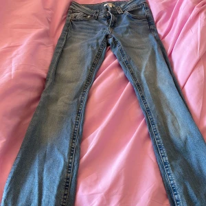 Blå jeansbyxor från Ginatricot - Säljer ett par klassiska blå jeansbyxor från Ginatricot med normal passform och raka ben. Byxorna har dubbla knappar i midjan, fem fickor och bälteshällor. Perfekta till vardags och lätta att matcha med olika toppar.