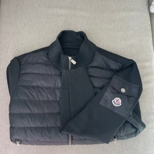 Monclerjacka - Cardigan zip från MONCLER. Skicket är bra förutom en liten söm som lossnat i nacken (se bild 4), vilket inte påverkar funktionen och är enkelt att lösa. Äkhetslapparna är tyvärr avklippta (se bild 5) därav priset, vid mer frågor kring det är det bara att skriva privat! Nypris 13 599kr. Storlek L och är specificerad till herr, men funkar för både herr och dam. Köparen står för frakten. Pris kan diskuteras vid snabb affär.