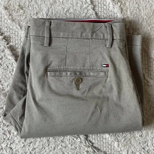 Beige shorts från Tommy Hilfiger - Snygga beige shorts från Tommy Hilfiger med klassisk passform. Shortsen har fickor fram och bak, bälteshällor och knappstängning. Liten broderad logga ovanför ena bakfickan. Perfekta för varma dagar.