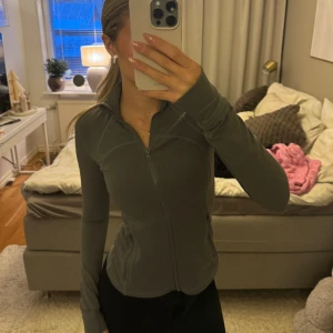 Grå träningsjacka med dragkedja - Snygg grå träningsjacka med dragkedja och hög krage. Jackan har en slim passform och långa ärmar, perfekt för träning eller vardagsbruk. Praktiska fickor med dragkedja framtill. Från Shein men väldigt bra kvalitet!