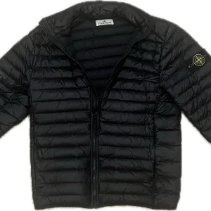 Stone Island Jacka (NyPris 7500) - Säljer en svart pufferjacka från Stone Island till ett extremt bra pris. med klassisk patch på ärmen. Jackan har dragkedja framtill och quiltad design som ger en modern look. Perfekt för kyligare dagar och enkel att matcha med olika outfits.