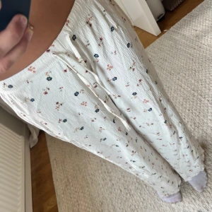 Vita blommiga mjukisbyxor med snörning - Säljer ett par vita mjukisbyxor med små blommiga mönster i rosa och blått. Säljer för jag sydde upp dom och de blev för korta😬Passar ngn som är 155 och under🩷