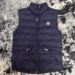 Mörkblå dunväst från Moncler - Snygg mörkblå dunväst från Moncler skick 9/10 ⚠️dragkedjan är lite trög du måste dra upp båda dragkedjorna för den ska funka⚠️ påse följer med 