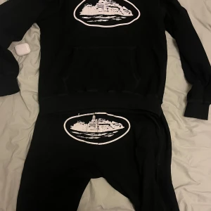 Svart hoodie med vit tryck - Säljer ett svart corteiz sätt då jag växt ur det. Sättet är i bra skick och väldigt snyggt, pris kan diskuteras. Bara att skriva för fler bilder