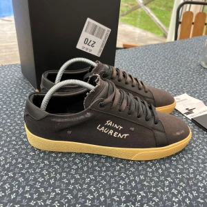 Saint Laurent skor  - Säljer ett par svarta Saint Laurent sneakers i mycket bra skick! Använda nån gång. Dom kan se lite bruna ut på bilderna men dom är svarta i verkligheten. Storlek 41 passar 42/42,5 också. Allt Og medföljer, box, kvitto och kort. Pris 3299kr. Mvh 
