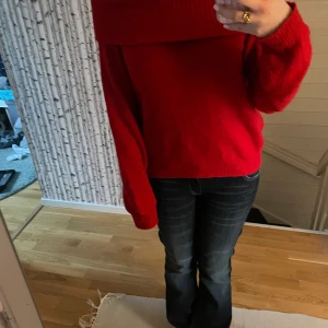 Röd stickad tröja från H&M - Säljer en mysig röd stickad tröja från H&M med en bred krage som kan bäras offshoulder. Perfekt för kyliga dagar och ger en stilren look. Tröjan har långa ärmar och en lös passform.
