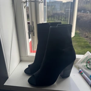 Svarta boots med öppen tå - Snygga svarta boots med öppen tå och klack. Perfekta för en stilren look. De har en elegant design som passar till många olika outfits.
