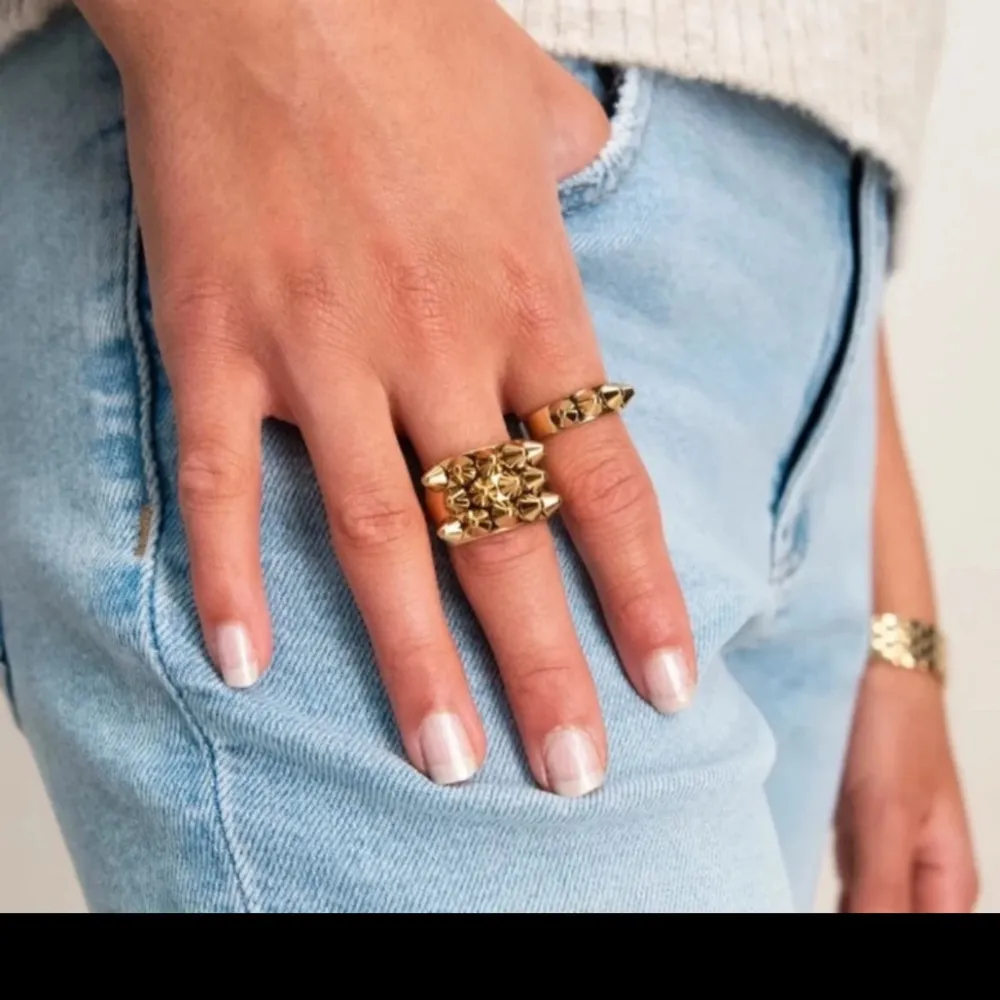 Snygg guldfärgad ring dekorerad med små nitar. Perfekt för att ge din outfit en edgy touch. Passar bra till både vardag och fest. 17.5 mm. Asusteet.