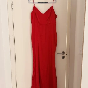 Röd långklänning från Nelly - Snygg röd långklänning från Nelly med smala axelband och v-ringning. Perfekt för festliga tillfällen. Klänningen har en elegant passform och en dragkedja i sidan för enkel påklädning. Det var för STOR och stretchigt så skulle passat någon fin☺️
