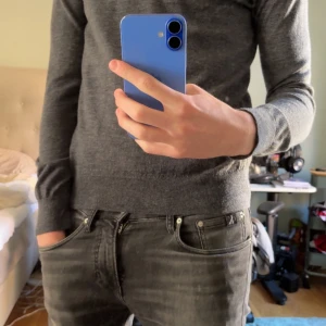 Grå merinoulltröja från Riley - Säljer en stilren grå tröja från Riley i mjuk merinoull. Perfekt för kyligare dagar med sin långärmade design och bekväma passform. Ett måste i garderoben för den som gillar klassisk stil.