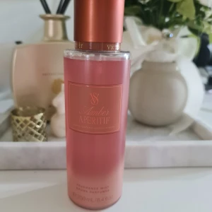 Amber Aperitif Fragrance Mist från Victoria's Secret - Säljer en Amber Aperitif Fragrance Mist från Victoria's Secret. Flaskan är rosa med en elegant kopparfärgad kork och rymmer 250 ml. Perfekt för en fräsch och lyxig doftupplevelse. Endast provsprayad, exakt som på bilderna!