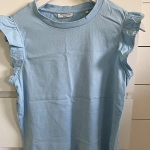 Ljusblå ärmlös topp från Marc O'Polo - Säljer en ljusblå ärmlös topp från Marc O'Polo med volangdetaljer vid axlarna. I storlek S och knappt använd💕