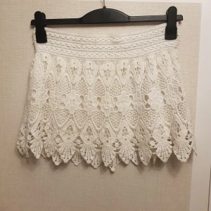 Vit spets kjol strl s/m 100% bomull - Charmig vit spets kjol i bomull med vackra detaljer. Kjolen har en kort längd och ett fint mönster som ger en romantisk känsla. Perfekt för varma dagar när du vill känna dig extra fin.