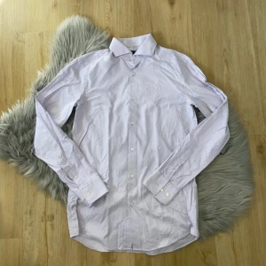 Röd skjorta från Boss - Säljer en stilren röd skjorta från Boss i egyptisk bomull. Skjortan har en slim fit passform och långa ärmar med knappar. Perfekt för en elegant look.