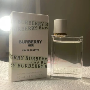 Burberry Her Eau de Toilette 30 ml - Säljer en elegant och fräsch Burberry Her Eau de Toilette i en stilren glasflaska med vit kork och gulddetaljer. Doften är lätt och feminin, perfekt för dagligt bruk. Flaskan rymmer 30 ml och kommer i en snygg förpackning med Burberry-loggan.