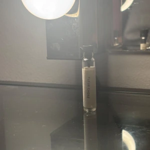 Fleur Créer parfymprov - Säljer ett parfymprov av Fleur Créer. Flaskan är liten och smidig, perfekt för att testa doften innan köp av en större flaska. Den har en enkel och stilren design med en vit etikett.