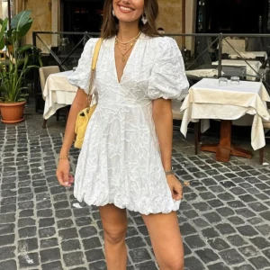 Vit klänning med puffärmar - Säljer en söt vit klänning med puffiga kortärmar och v-ringning. Klänningen har ett fint broderat mönster. Perfekt för studenten och sommarens alla stunder💕