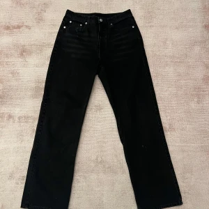 Svarta jeansbyxor från Rowe - Snygga svarta jeansbyxor från Rowe med en klassisk design. Byxorna har en rak passform och är perfekta för en stilren look. De har knappar och dragkedja framtill.