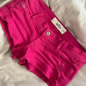 Rosa shorts från Hollister - Snygga rosa shorts från Hollister med fransiga detaljer och låg midja. Perfekta för sommardagar och strandhäng. De har en klassisk femficksdesign och en dragkedjegylf. Skriv vid intresse💕