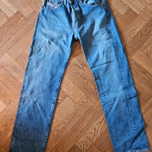 Blå jeans från Diesel - Klassiska blå jeans från Diesel med raka ben och femficksdesign. Byxorna har normal passform och tydliga sömmar på bakfickorna. Perfekta för dig som gillar en tidlös denimlook.