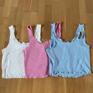 Ribbade croppade linnen i vitt, rosa och blått  - Tre croppade linnen från SHEIN i ribbat material. Färgerna är vit, rosa och ljusblå. Modellen har breda axelband och vågig kant nertill. Perfekta för varma dagar eller som layering-plagg. Säljer alla tre ihop eller en och en!