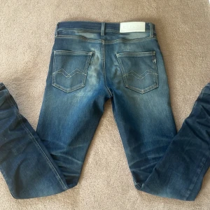 Replay Wallys Super Slim jeans - Säljer ett par blå Replay Wallys jeans med super slim passform. Jeansen har klassisk femficksdesign, snygga slitningar och ljusare partier på låren och bak. Märke på linningen och dragkedja i gylfen. Perfekta för dig som gillar tajta jeans med modern look. Fickorna har blivit uppslitet som ni ser på sista bilden men påverkar såklart inte jeansen