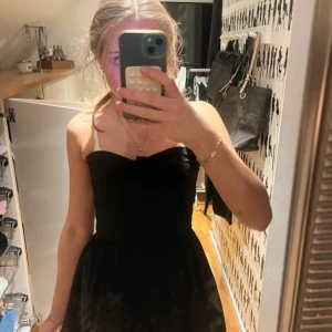 Svart axelbandslös klänning från Jeane Blush - Säljer en svart axelbandslös klänning från Jeane Blush i storlek S. Klänningen har knappar framtill och en markerad midja. 