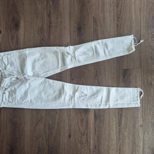 Vita super skinny jeans från H&M - Säljer ett par vita super skinny jeans från H&M. Byxorna har råa benslut och klassisk femficksdesign. De är tighta hela vägen och med slitningar look