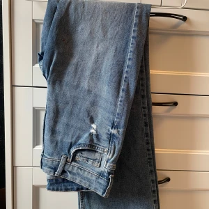 Blå bootcut jeans - Säljer ett par klassiska blå bootcut jeans med normal passform. Tyvärr har jag spillt nagellack på dem men det är inget som syns så tydligt.