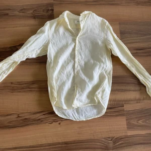 Vit linneskjorta från Uniqlo - Säljer en klassisk vit skjorta från Uniqlo i svalt och skönt linne. Skjortan har lång ärm, knappar framtill och en avslappnad passform. Perfekt till sommaren för en stilren och enkel look.